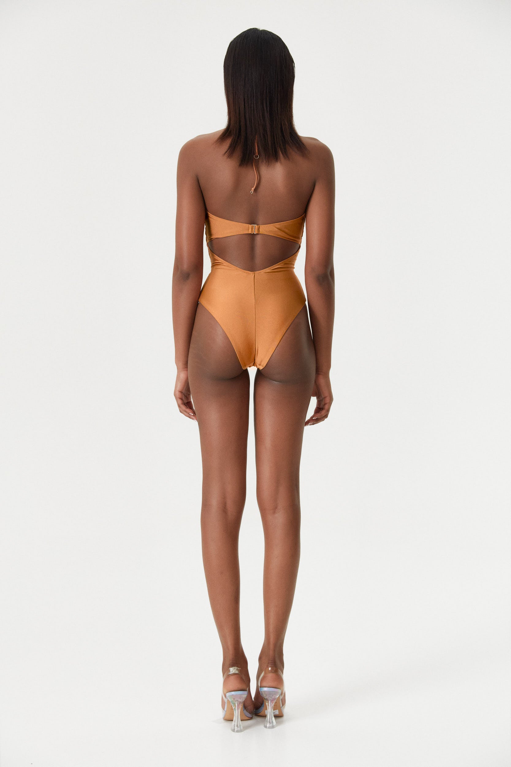 Rear view of the model in the Amber Infinity One-Piece, emphasizing the elegant low open back and soft satin material.